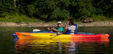 two men having a conversation while canoeing in river