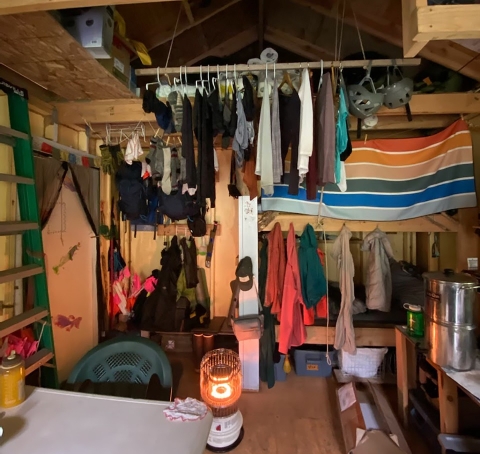 Raingear and clothes hang to dry in a small cabin.