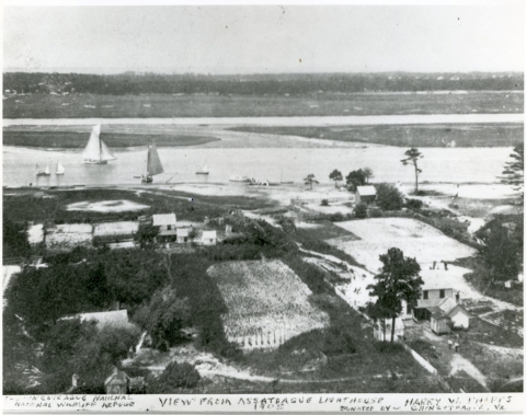 A black and white photo of a small community with fields and sail boats