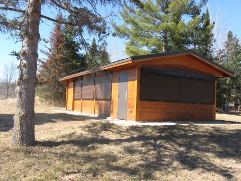 Small wood building with pine trees in the background