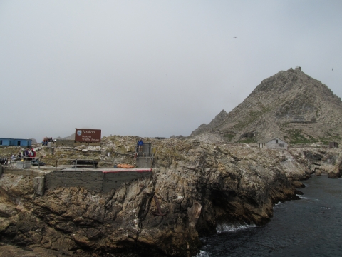 Rocky island with a flat platform with hand rails and a large sign with the text, Farallon National Wildlife Refuge. 