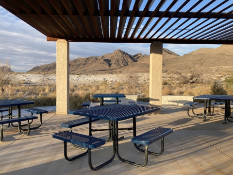 Pavilion with 4 blue picnic tables and a view of a desert mountain