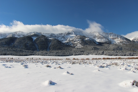 Clouds begin to form over snowy mountains on a bluebird day.