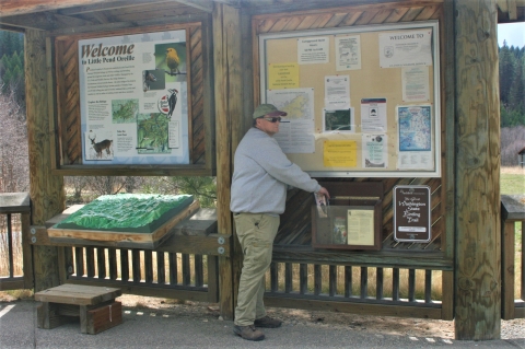 USFWS Volunteer putting brochures into an information kiosk