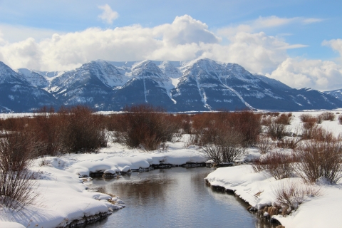 A wintery view of the mountains as seen from a creek in the foreground