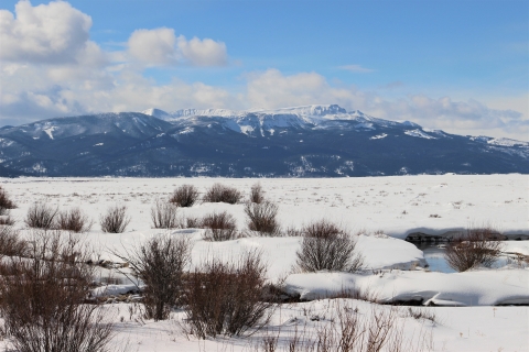 A snowy mountain in winter looking out over a snowy valley