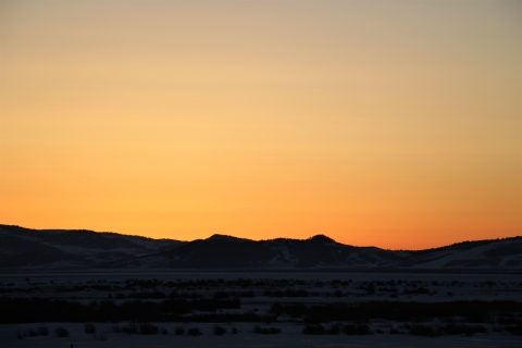 A brilliant early morning orange sunrise in winter is shown.