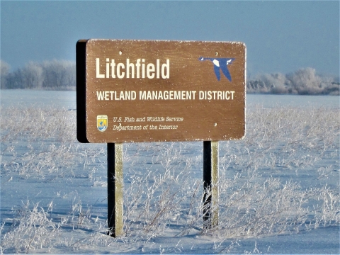 Litchfield Wetland Management District sign on a snowy landscape. 
