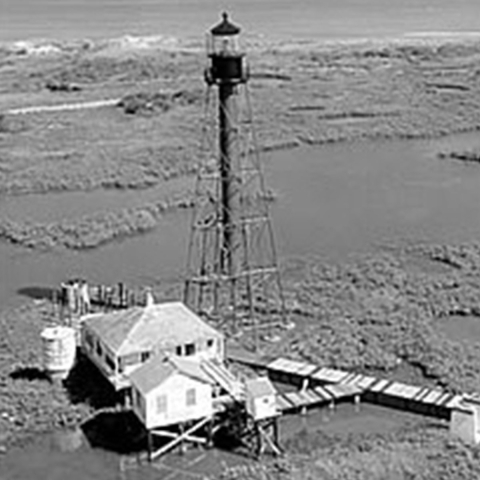 Lighthouse in marsh with a adjacent elevated house and boardwalks