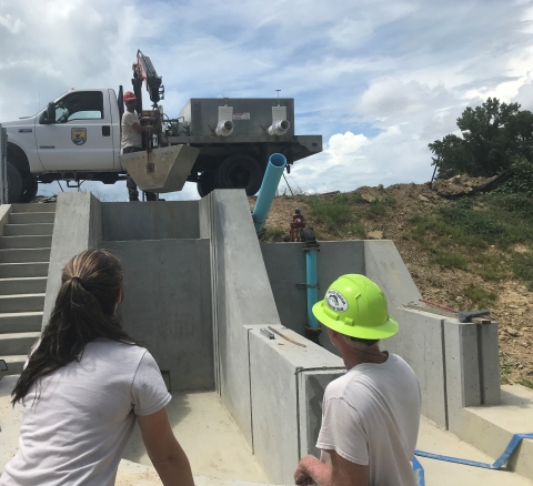 Edenton NFH staff lower bucket with a crane into dry kettle as a test before adding fish to pond.
