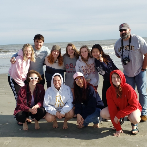 Eleven Appalachian State University students grouped for photo with the ocean behind them at Bulls Island. on the Bulls