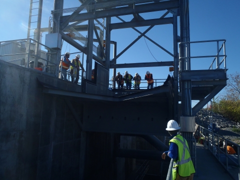 people in hard hats and construction vests on dam structure