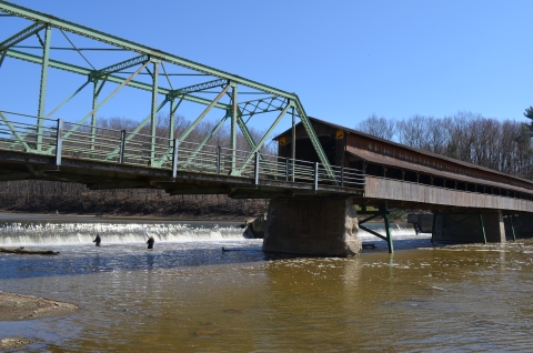 A river with a bridge and anglers along a low dam