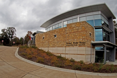 A three level building with glass windows and stones in the front. 