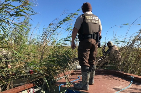 An image of a Federal Wildlife Officer standing on a boat.
