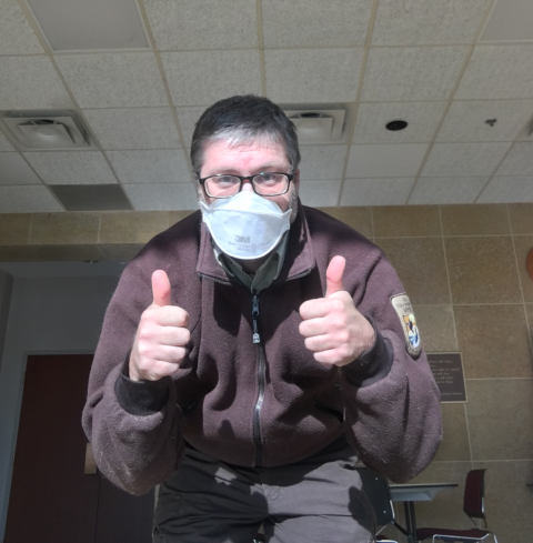 U.S. Fish & Wildlife male ranger masked with thumbs up inside building
