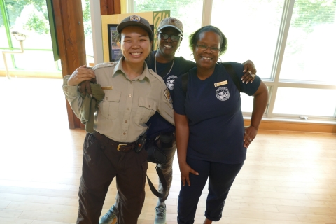 An uniformed ranger smiles with two refuge volunteers inside the Visitor Center at John Heinz National Wildlife Refuge at Tinicum.