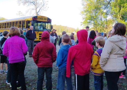 Refuge staff talking to students by school bus