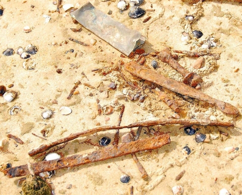 Rusted primitive tools lying on sand and pebbles