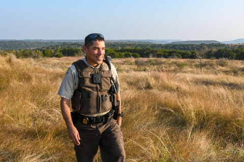 a law enforcement officer smiles and walks across the landscape