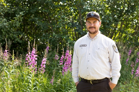 man in fish and wildlife uniform by fireweed