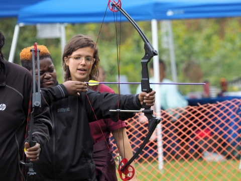 A young woman coaches a visitor in archery at John Heinz Refuge in Philadelphia.