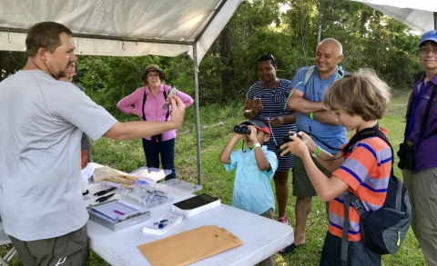 Biologist Aaron Givens holds a banded bird for children to see at the banding table during the Bulls Bay Nature Festival.