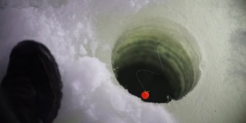 a foot by an ice fishing hole in the ice