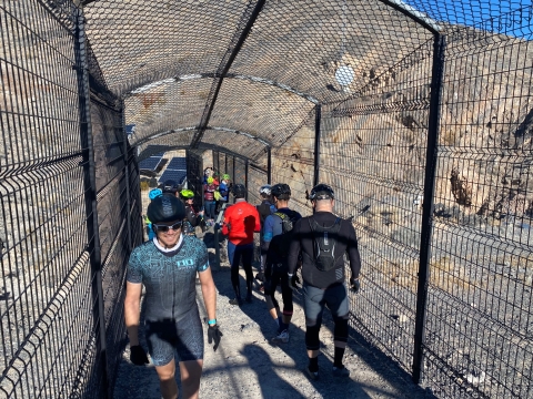 people walk through a fenced tunnel to Devils Hole