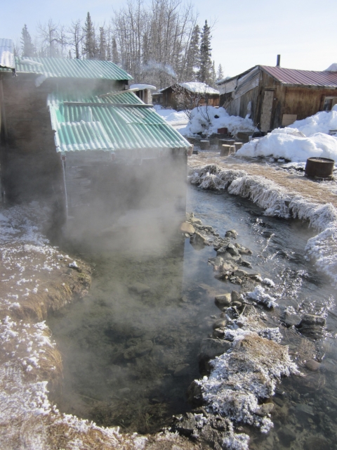 steaming pool of water in front of wooden buildings