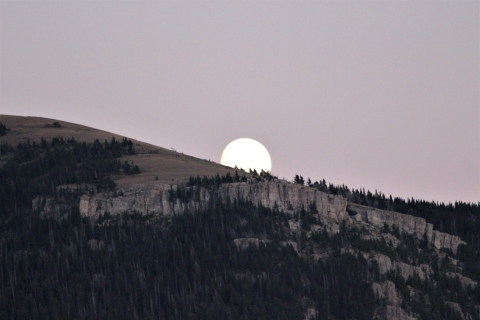 A full moon rises over a mountain