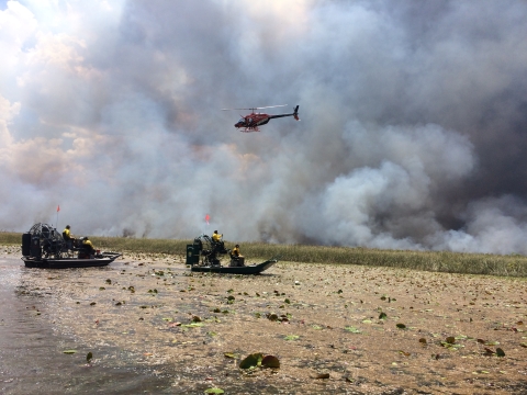 A helicopter hovers near smoked-filled air at the site of a prescribed fire.
