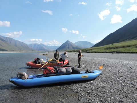 Three people load rafts for a river trip at Arctic National Wildlife Refuge.