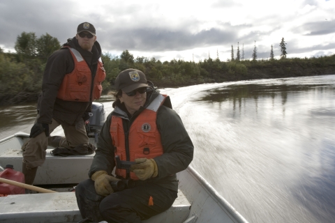 two people in US Fish and Wildlife Service uniforms riding in a motorboat