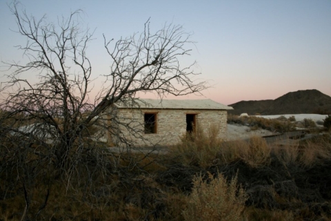 a small, one-story, stone cabin sits in the middle of the desert