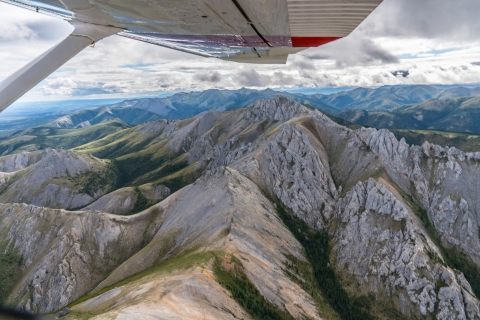 view from the window of a small aircraft wing and mountainous scenery