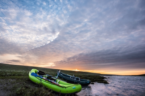 two rafts rest on the bank of a river at sunset