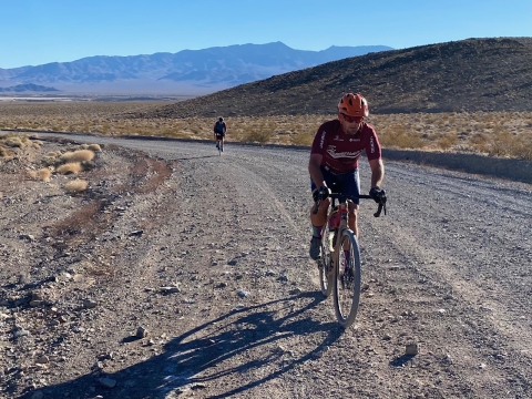 cyclists climb up a dirt road in the desert