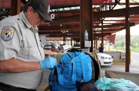 A wildlife inspector inspects a blue backpack.