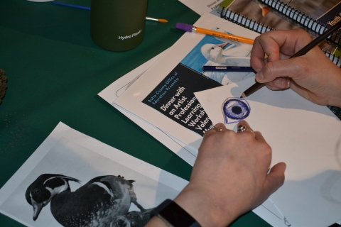 A person draws a duck eye as a part of a JDS Workshop in 2019.