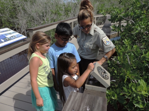 Supervisory Refuge Ranger Toni Westland joins kids exploring a scat panel on the Education Boardwalk Trail at J.N. "Ding" Darling National Wildlife Refuge in Florida.
