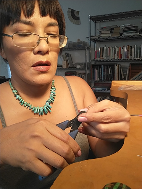 Liz Wallace, a jeweler and an enrolled member of the Navajo Nation, cuts silver wire in the process of making a piece of jewelry