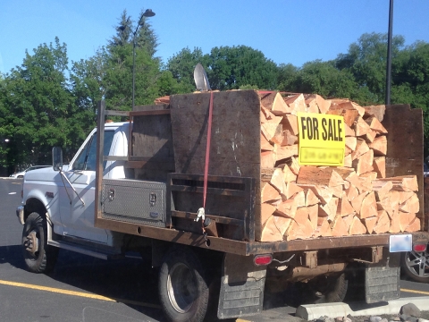 White flat-bed truck carrying stacks of wood. 