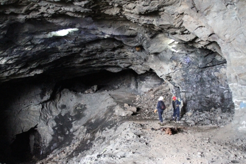 Two people standing in the mouth of an underground cavern
