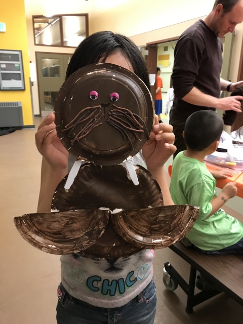 Child holds walrus mask up to face. 