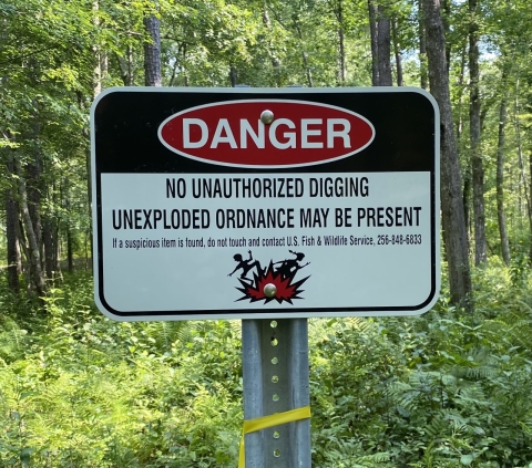 A warning sign that reads:No unauthorized digging unexploded ordnance may be present. If a suspicious item is found, do not touch and contact U.S.