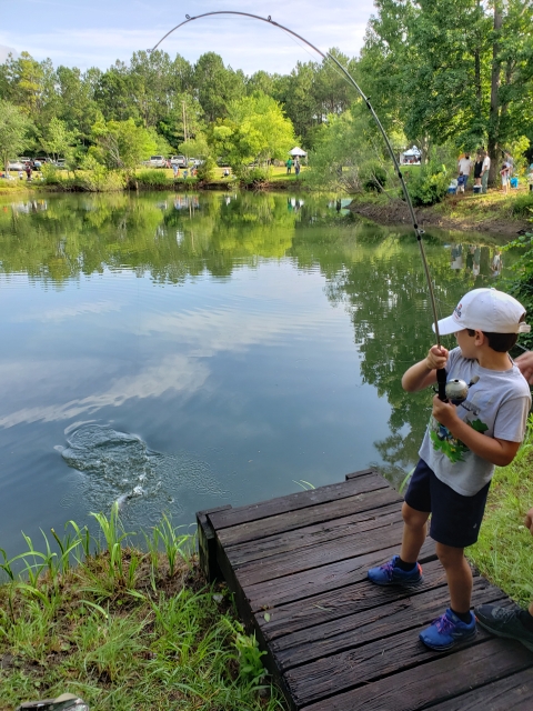 Fish bit the lure and a young angler is battling with a bent fishing rod