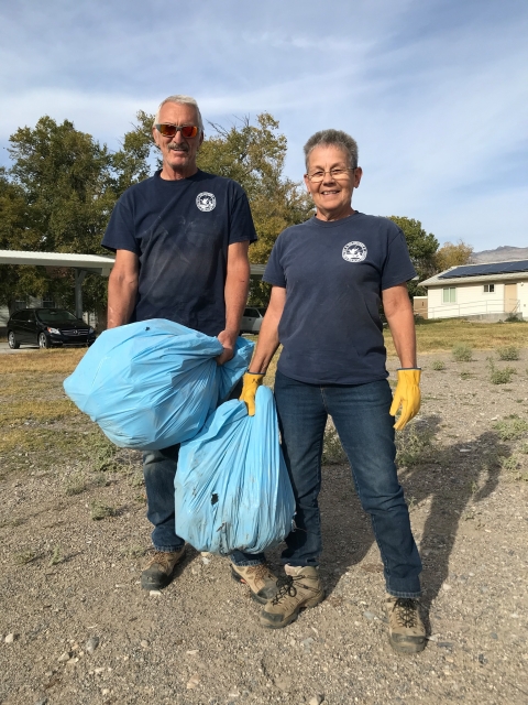 Two volunteers hold large bags of trash collected on the refuge