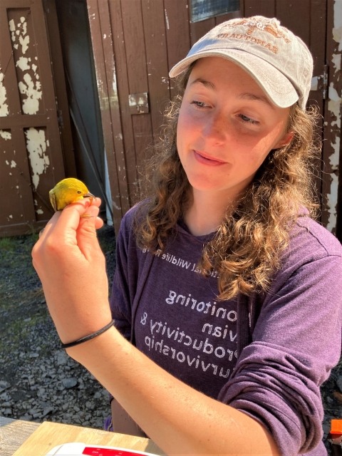 Woman in a purple hoodie holding a small yellow bird
