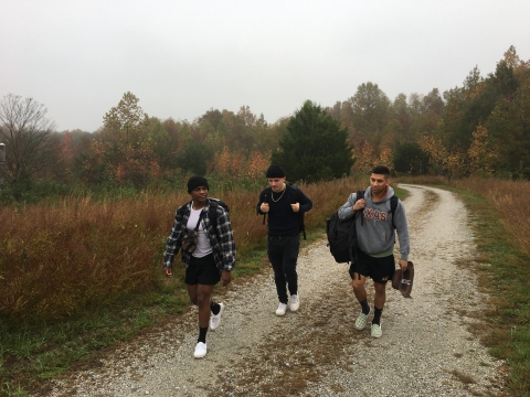 Three people walk on a gravel trail. 